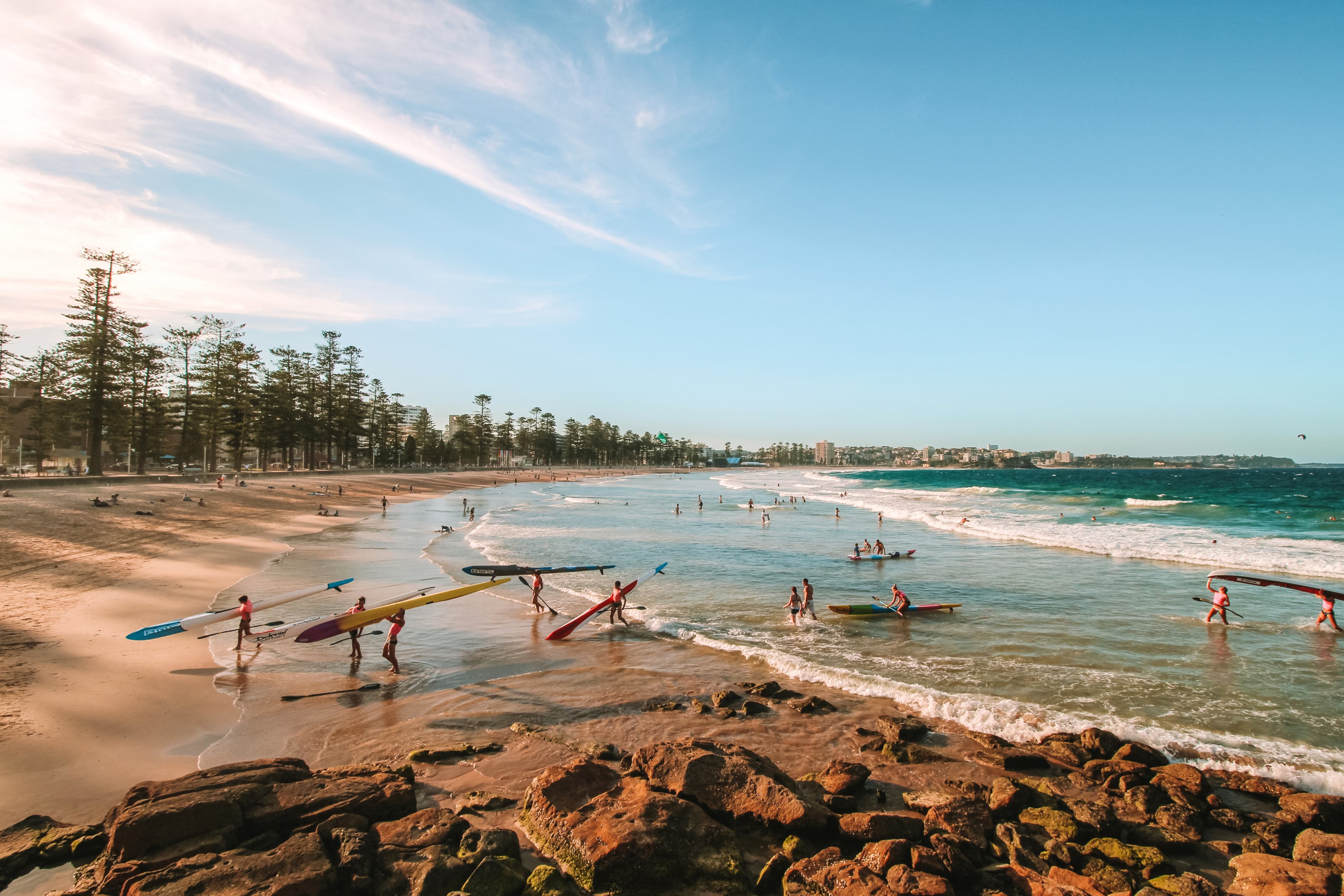 Surf lifesavers carrying boards along an Australian beach